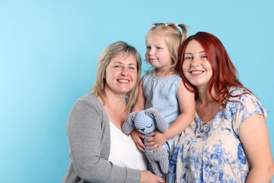 Photo of Grandmother, her daughter and granddaughter on light blue background