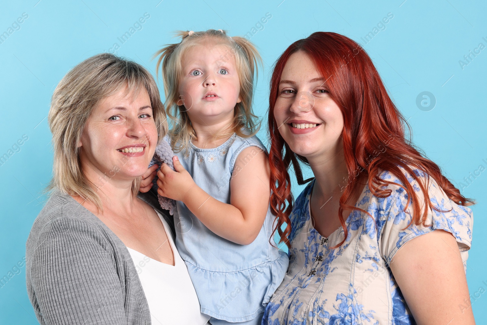 Grandmother, her daughter and granddaughter on light blue background Photo of Grandmother, her daughter and granddaughter on light blue background