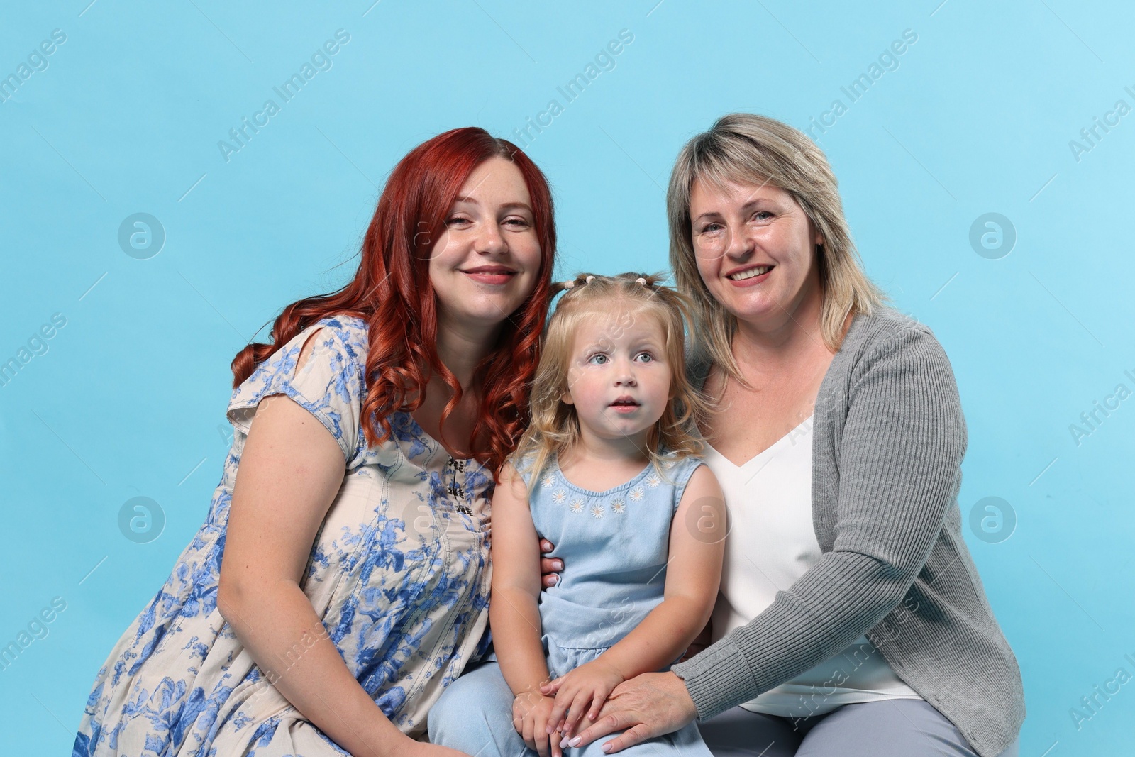 Pregnant woman, her mother and daughter on light blue background Photo of Pregnant woman, her mother and daughter on light blue background