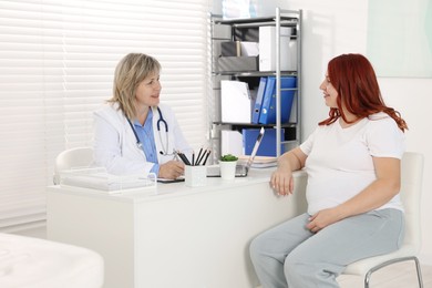 Photo of Pregnant woman having appointment with doctor in clinic