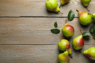 Photo of Fresh ripe pears and green leaves on wooden table, flat lay. Space for text