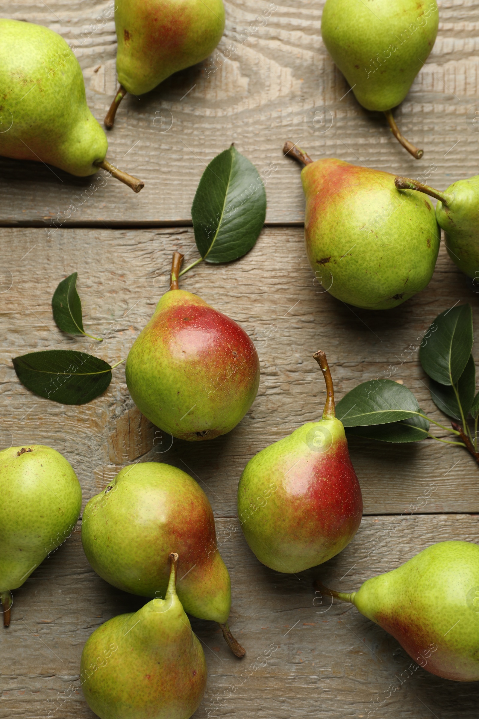 Photo of Fresh ripe pears and green leaves on wooden table, flat lay