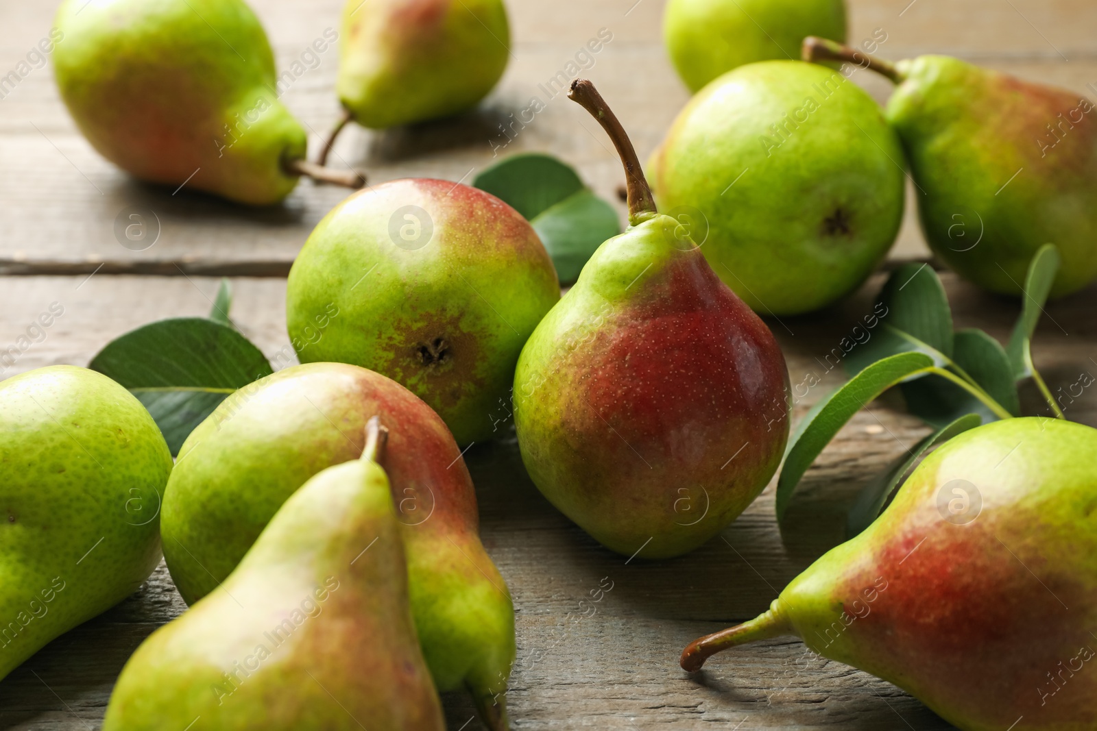 Photo of Fresh ripe pears and green leaves on wooden table, closeup