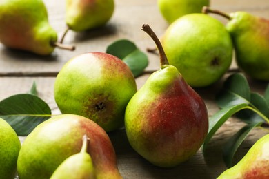 Photo of Fresh ripe pears and green leaves on wooden table, closeup