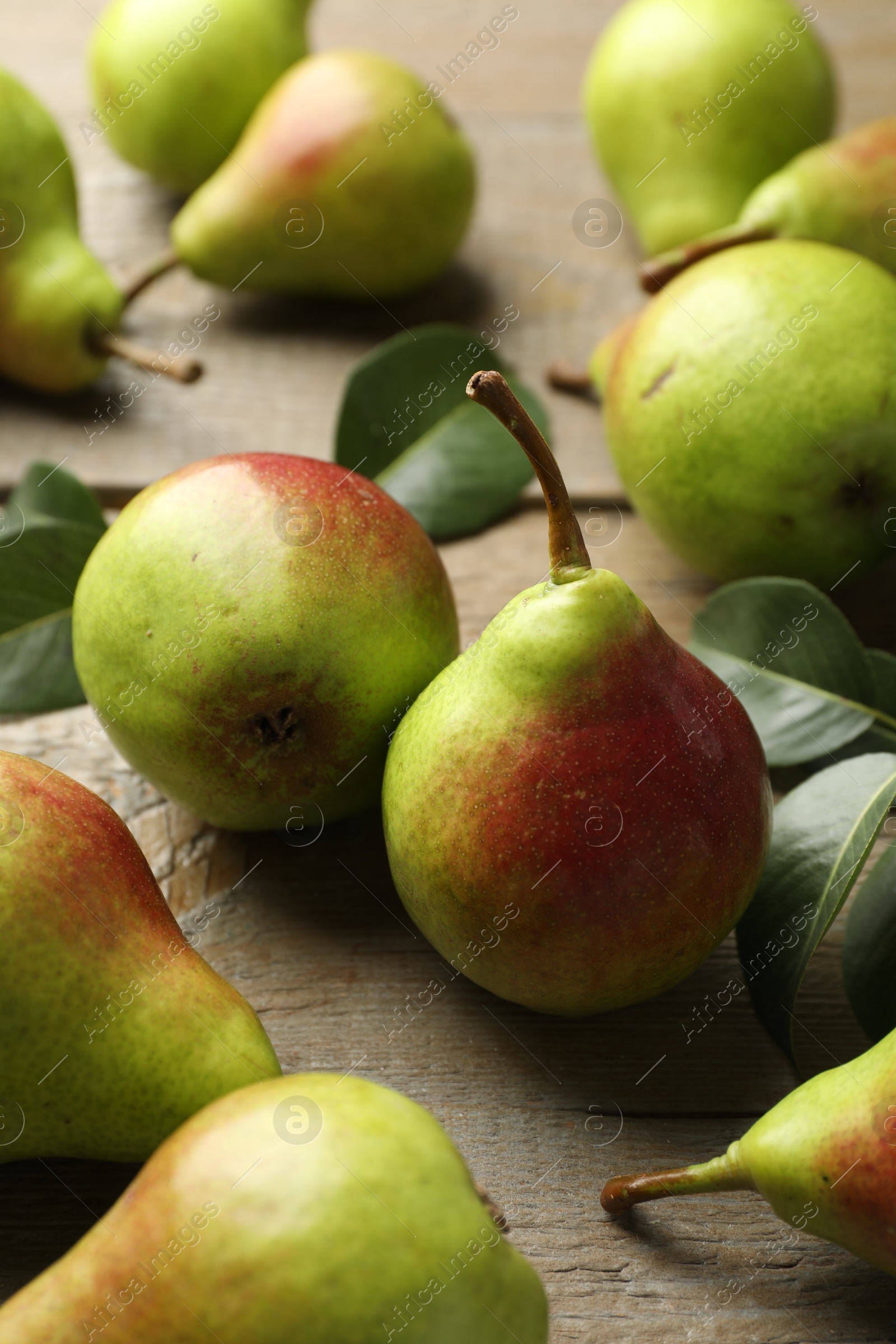 Photo of Fresh ripe pears and green leaves on wooden table, closeup