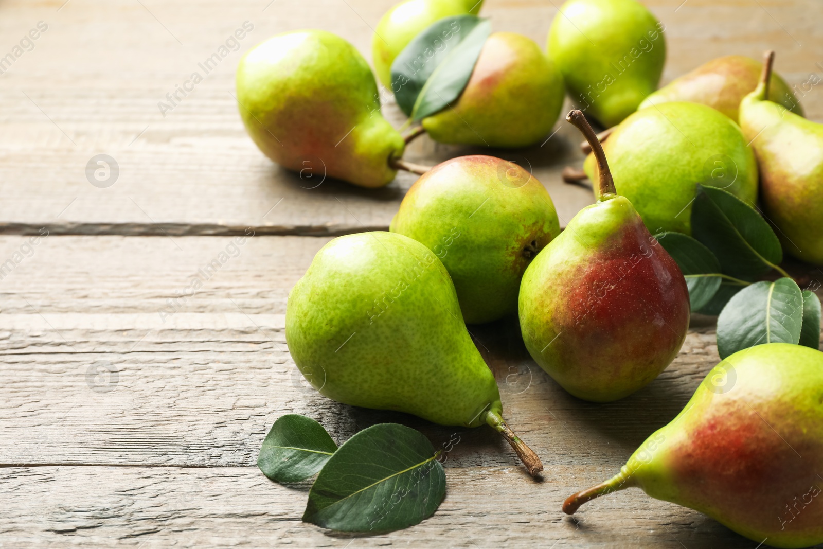 Photo of Fresh ripe pears and green leaves on wooden table, closeup. Space for text
