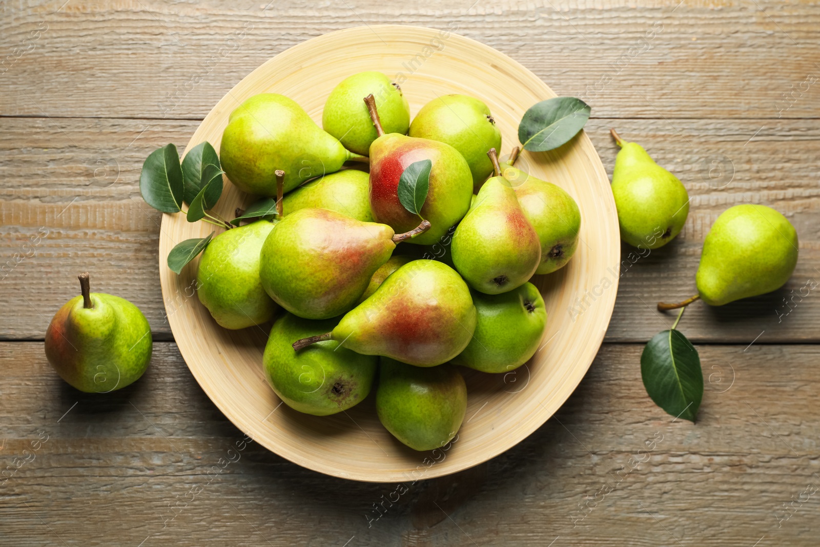 Photo of Fresh ripe pears and green leaves on wooden table, flat lay