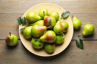 Photo of Fresh ripe pears and green leaves on wooden table, flat lay
