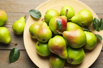 Photo of Fresh ripe pears and green leaves on wooden table, flat lay