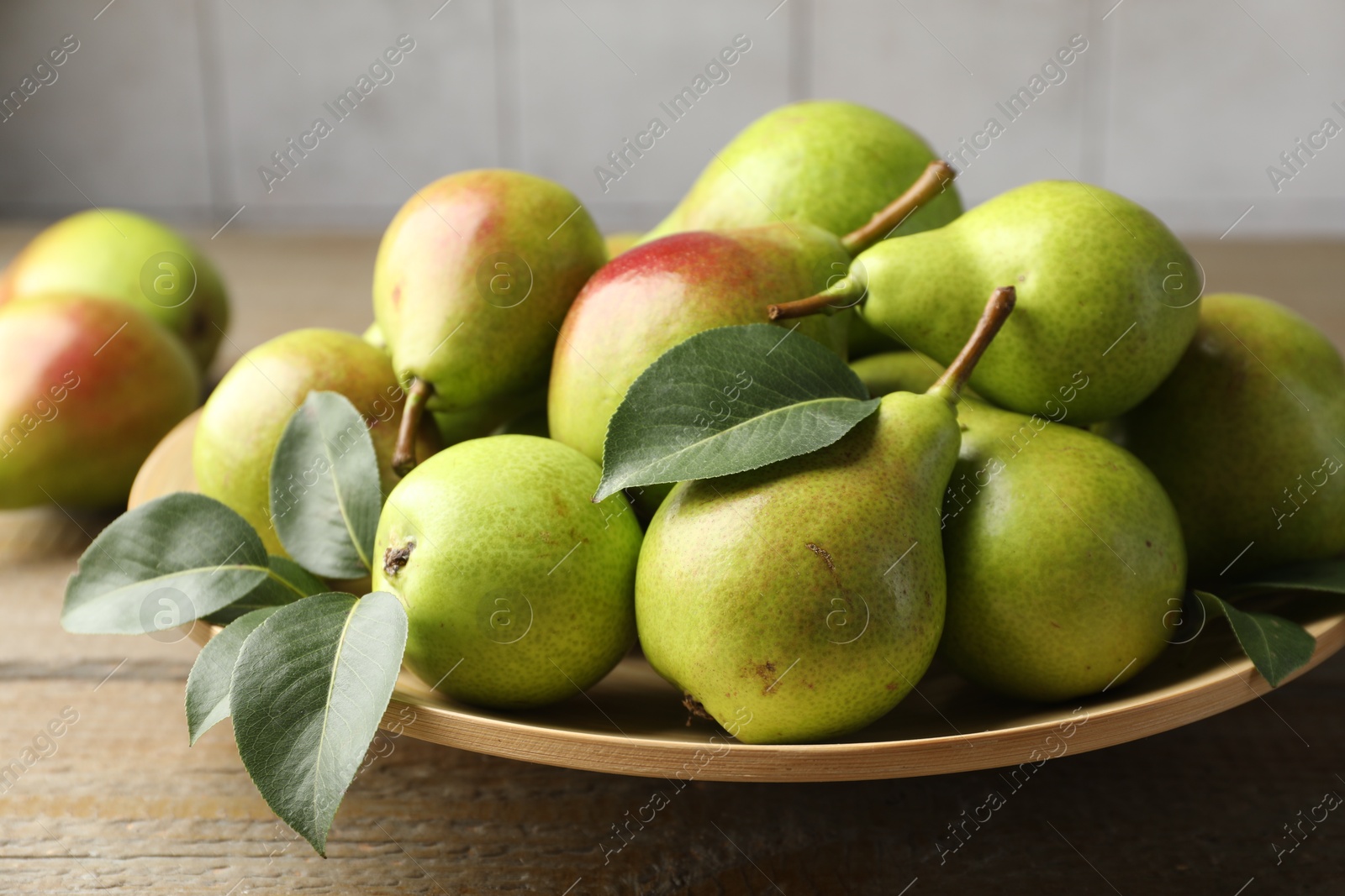 Photo of Fresh ripe pears and green leaves on wooden table, closeup