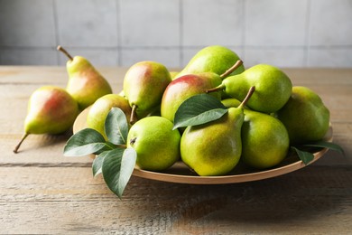 Photo of Fresh ripe pears and green leaves on wooden table, closeup