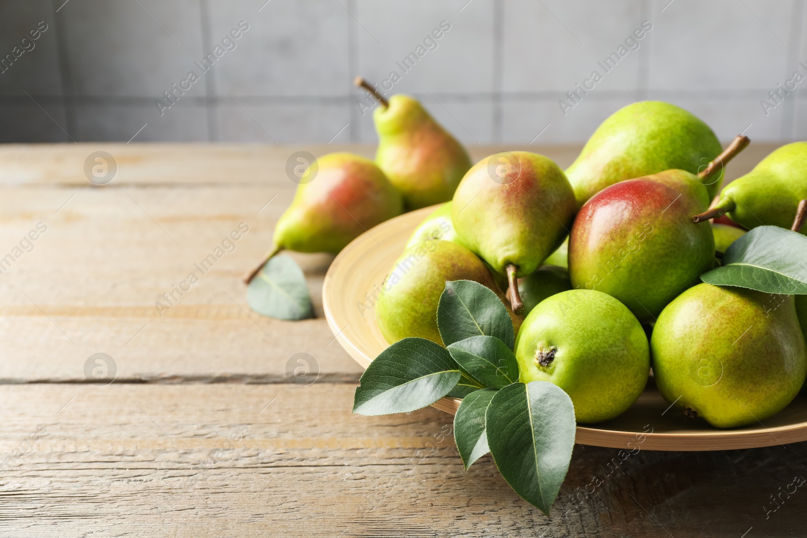 Photo of Fresh ripe pears and green leaves on wooden table, closeup. Space for text