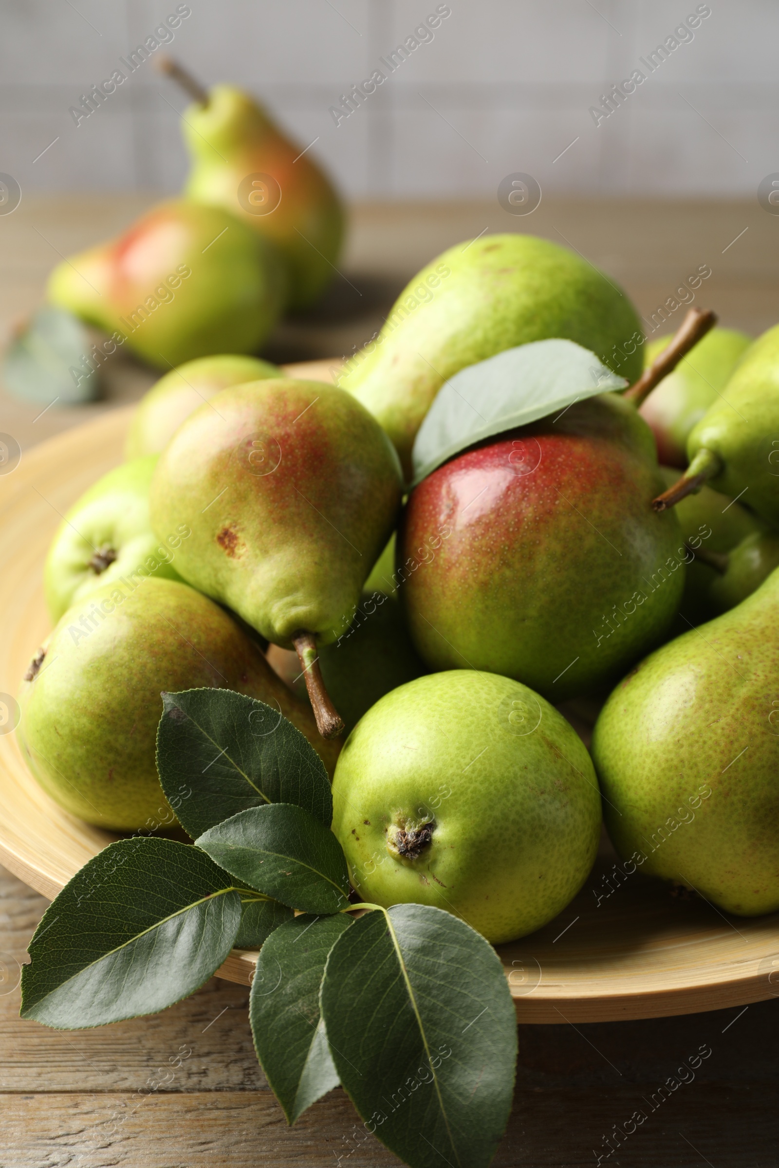 Photo of Fresh ripe pears and green leaves on wooden table, closeup