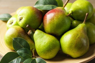 Photo of Fresh ripe pears and green leaves on table, closeup