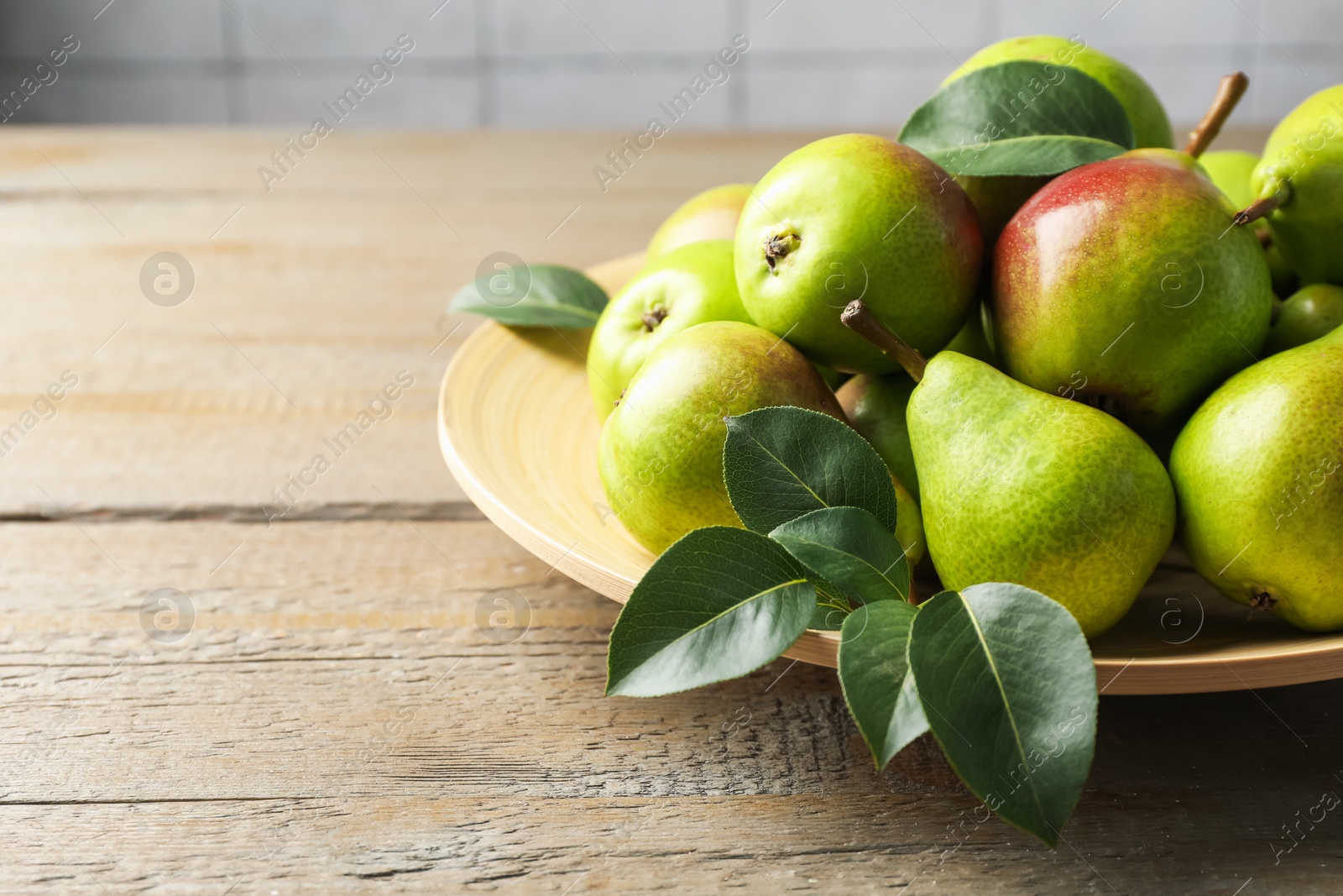 Photo of Fresh ripe pears and green leaves on wooden table, closeup. Space for text