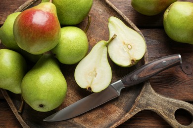 Photo of Fresh ripe pears and knife on wooden table, top view