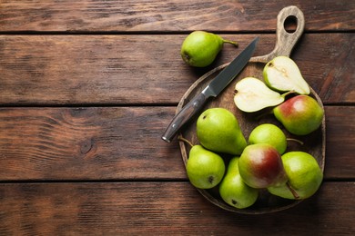 Photo of Fresh ripe pears and knife on wooden table, top view. Space for text
