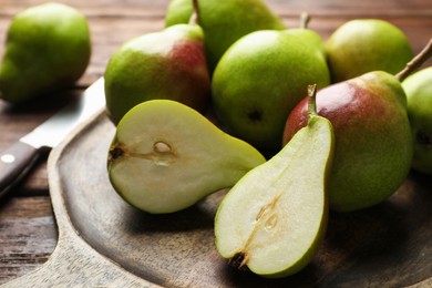 Photo of Fresh ripe pears and knife on wooden table, closeup