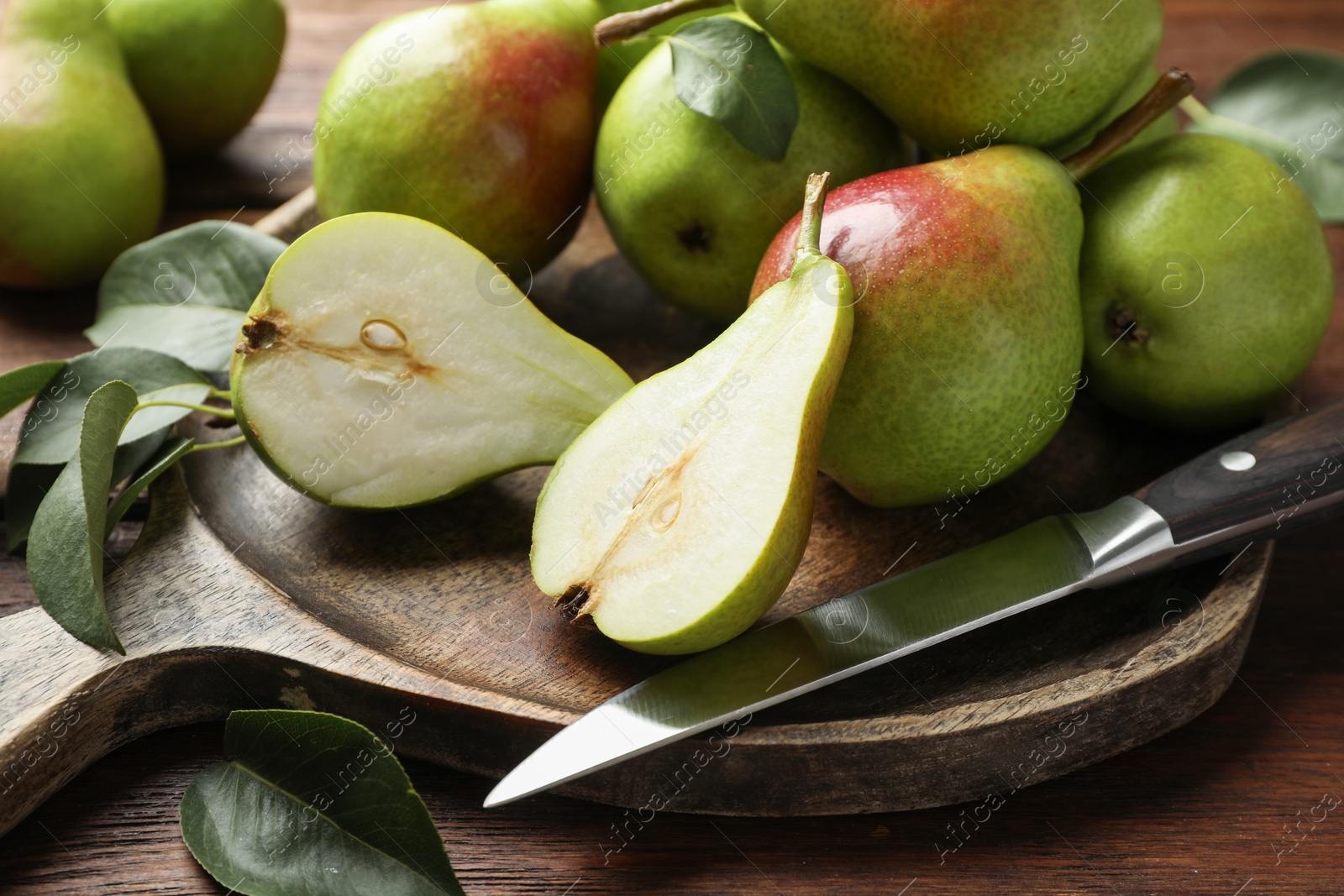 Photo of Fresh ripe pears and knife on wooden table, closeup