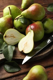 Photo of Fresh ripe pears and knife on wooden table, closeup