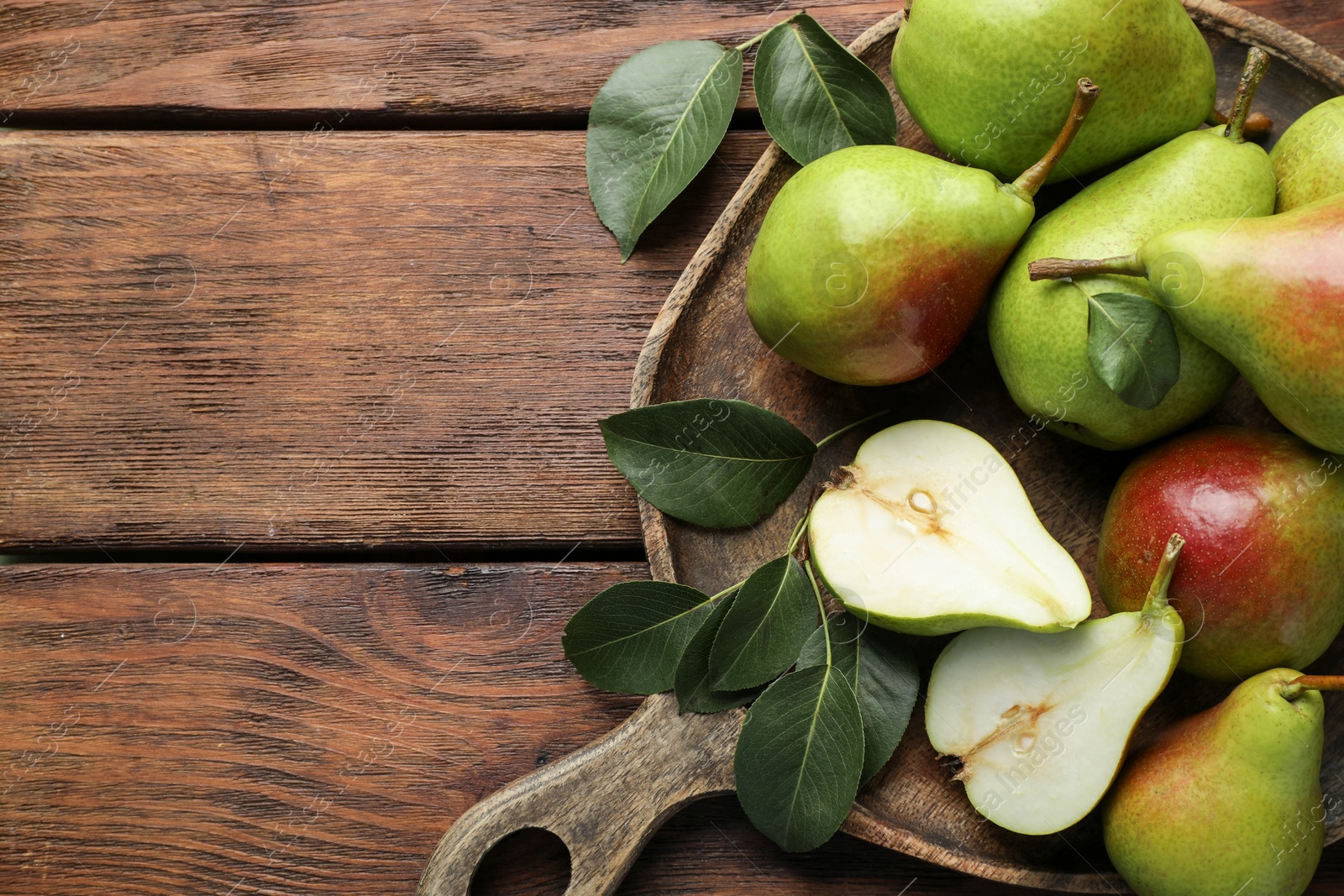 Photo of Fresh ripe pears and green leaves on wooden table, top view. Space for text