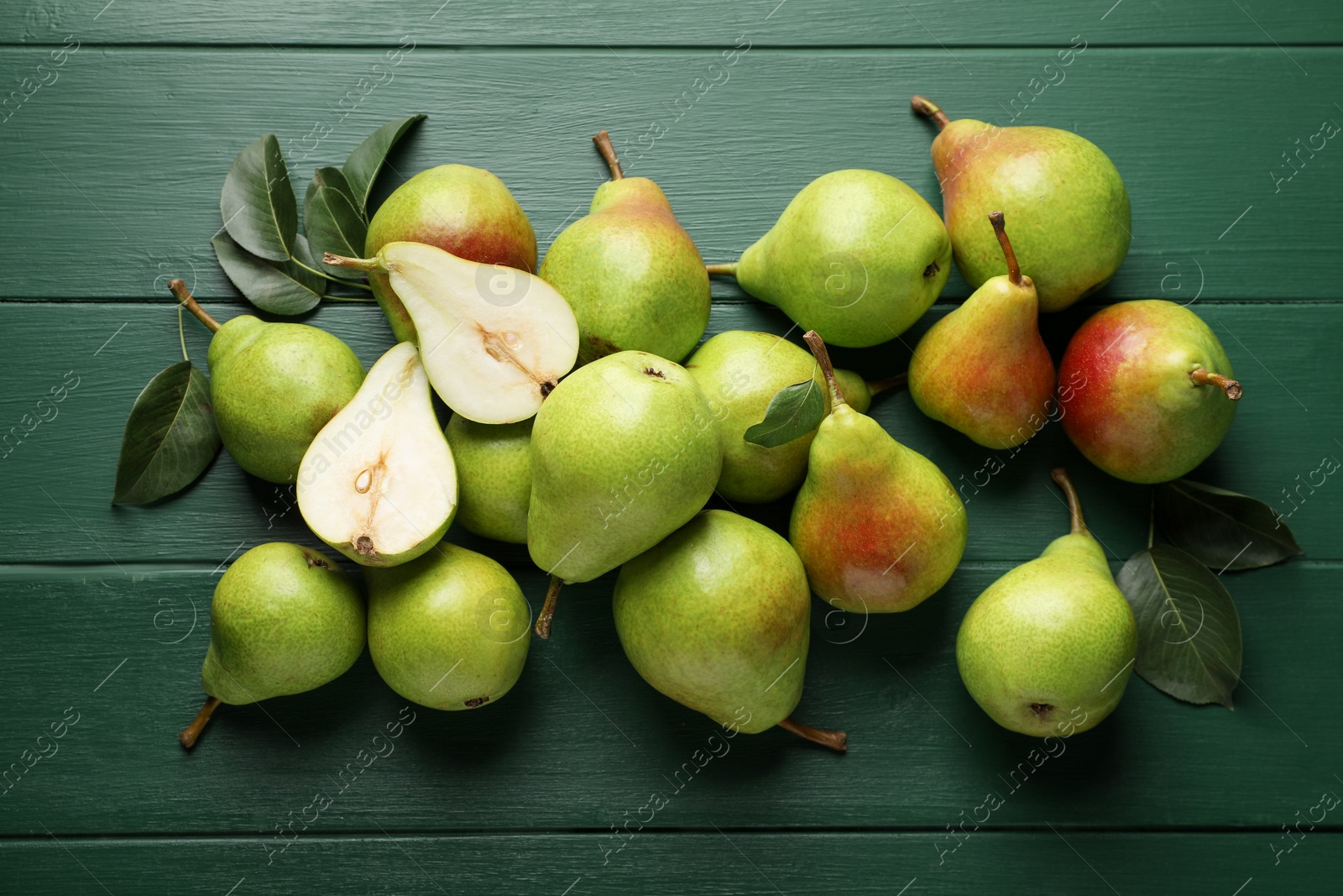 Fresh ripe pears and leaves on green wooden table, flat lay Photo of Fresh ripe pears and leaves on green wooden table, flat lay