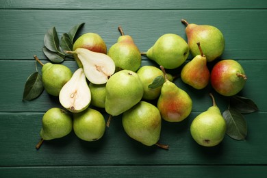 Photo of Fresh ripe pears and leaves on green wooden table, flat lay