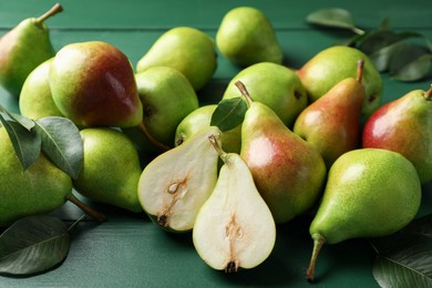 Photo of Fresh ripe pears and leaves on green wooden table, closeup