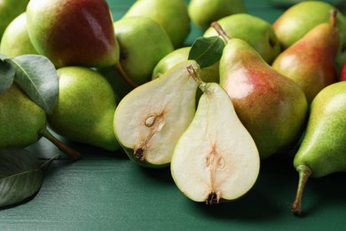 Photo of Fresh ripe pears and leaves on green wooden table, closeup