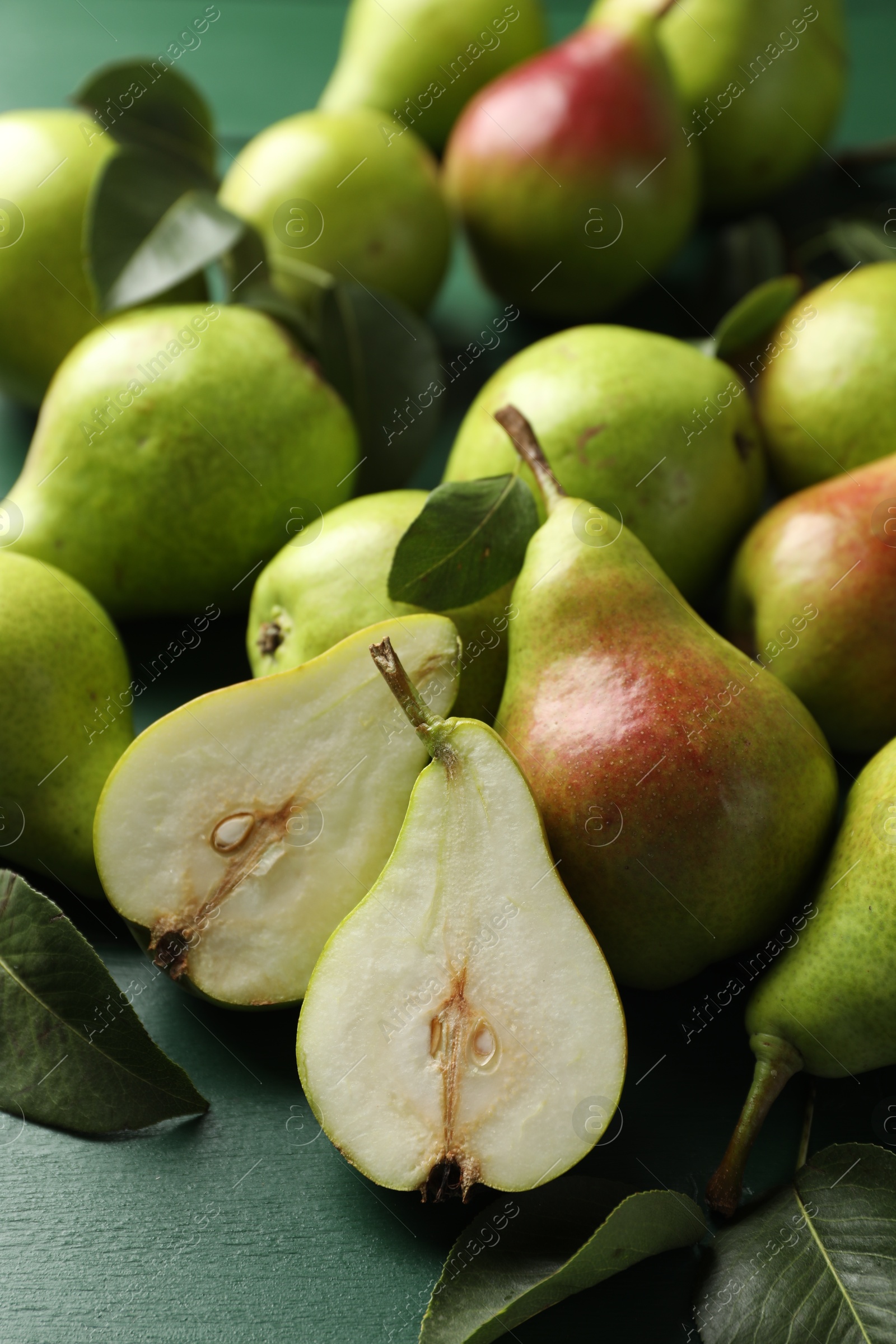 Photo of Fresh ripe pears and leaves on green wooden table, closeup