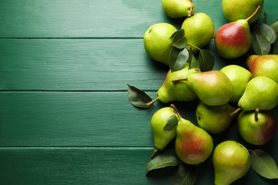 Photo of Fresh ripe pears and leaves on green wooden table, flat lay. Space for text
