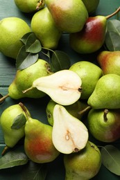 Photo of Fresh ripe pears and leaves on green wooden table, flat lay