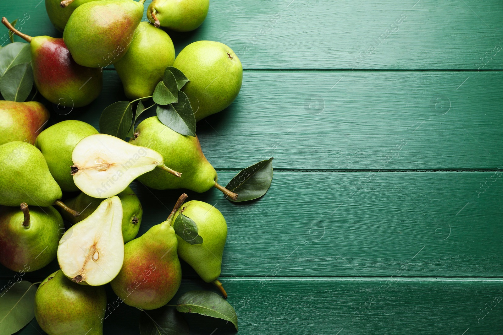 Photo of Fresh ripe pears and leaves on green wooden table, flat lay. Space for text