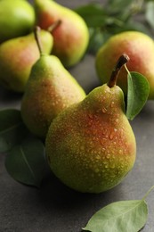 Photo of Fresh ripe pears and green leaves on grey table, closeup