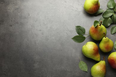 Photo of Fresh ripe pears and green leaves on grey table, flat lay. Space for text
