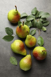 Photo of Fresh ripe pears and green leaves on grey table, flat lay