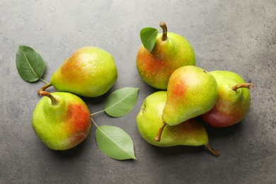 Photo of Fresh ripe pears and green leaves on grey table, flat lay