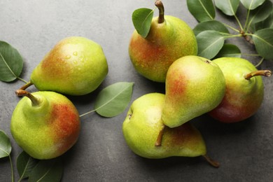 Photo of Fresh ripe pears and green leaves on grey table, flat lay