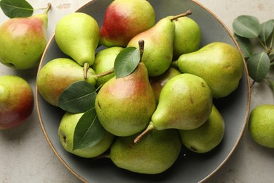 Photo of Fresh ripe pears and green leaves on light grey table, flat lay