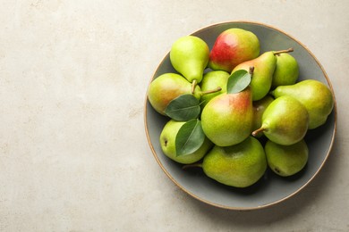 Photo of Fresh ripe pears and green leaves on light grey table, top view. Space for text