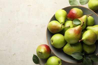 Photo of Fresh ripe pears and green leaves on light grey table, flat lay. Space for text