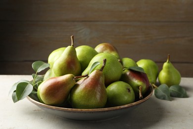 Photo of Fresh ripe pears and green leaves on light grey table, closeup