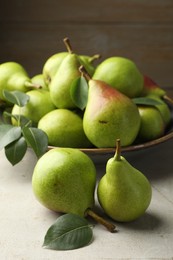 Photo of Fresh ripe pears and green leaves on light grey table, closeup