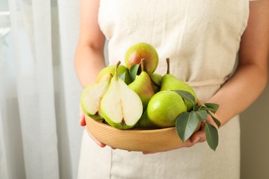 Photo of Woman with fresh ripe pears and green leaves indoors, closeup