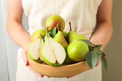 Photo of Woman with fresh ripe pears and green leaves indoors, closeup