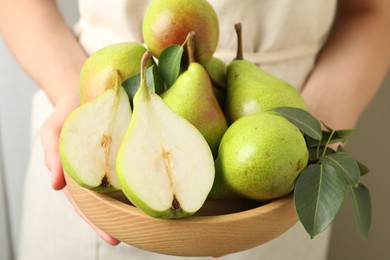 Photo of Woman with fresh ripe pears and green leaves indoors, closeup
