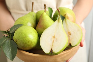 Photo of Woman with fresh ripe pears and green leaves indoors, closeup