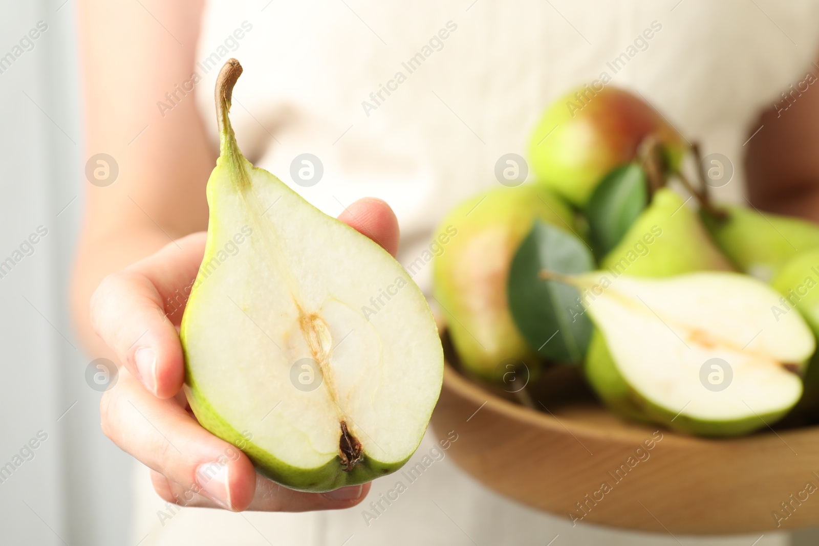 Photo of Woman with fresh ripe pears and green leaves indoors, closeup