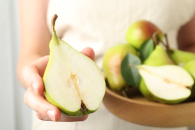 Photo of Woman with fresh ripe pears and green leaves indoors, closeup