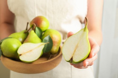 Photo of Woman with fresh ripe pears and green leaves indoors, closeup
